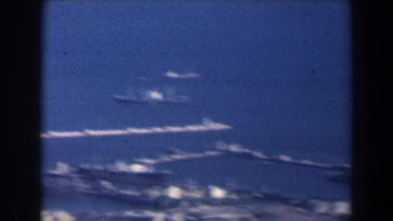 Blue sea with several small ships and a dark vertical obstruction at the frame edge.