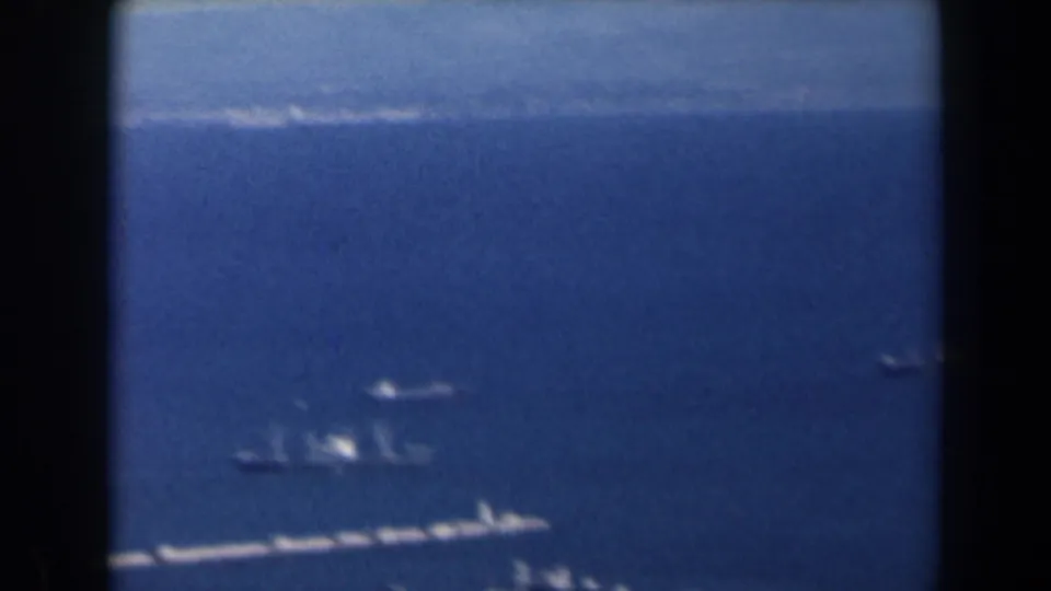 1960 Israel 8mm aerial view across open water toward a hazy shoreline with small vessels below.