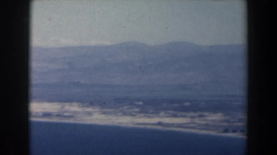 1960 Israel 8mm frame looking over sea and shoreline toward hazy inland mountains.
