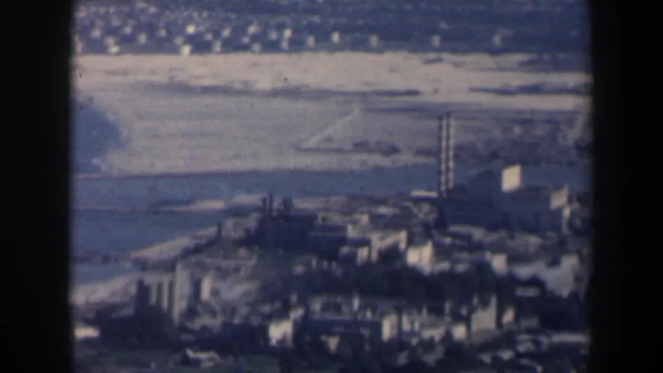 1960 Israel aerial view with industrial-looking structures, tall stacks, pale fields and water visible below.