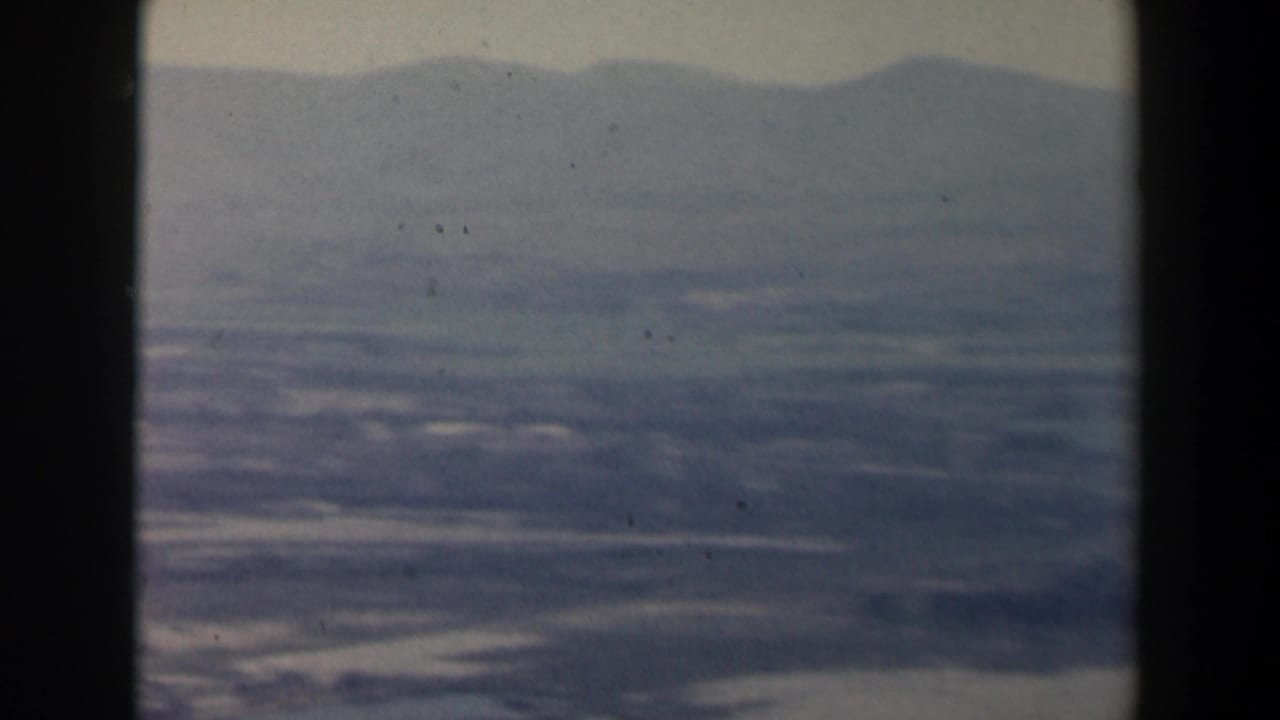 Aerial view over hazy Israeli fields and mountain ridges, partly obscured by a dark vertical window divider.