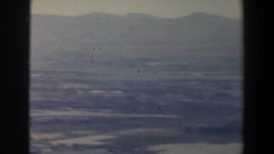 Aerial view over hazy Israeli fields and mountain ridges, partly obscured by a dark vertical window divider.