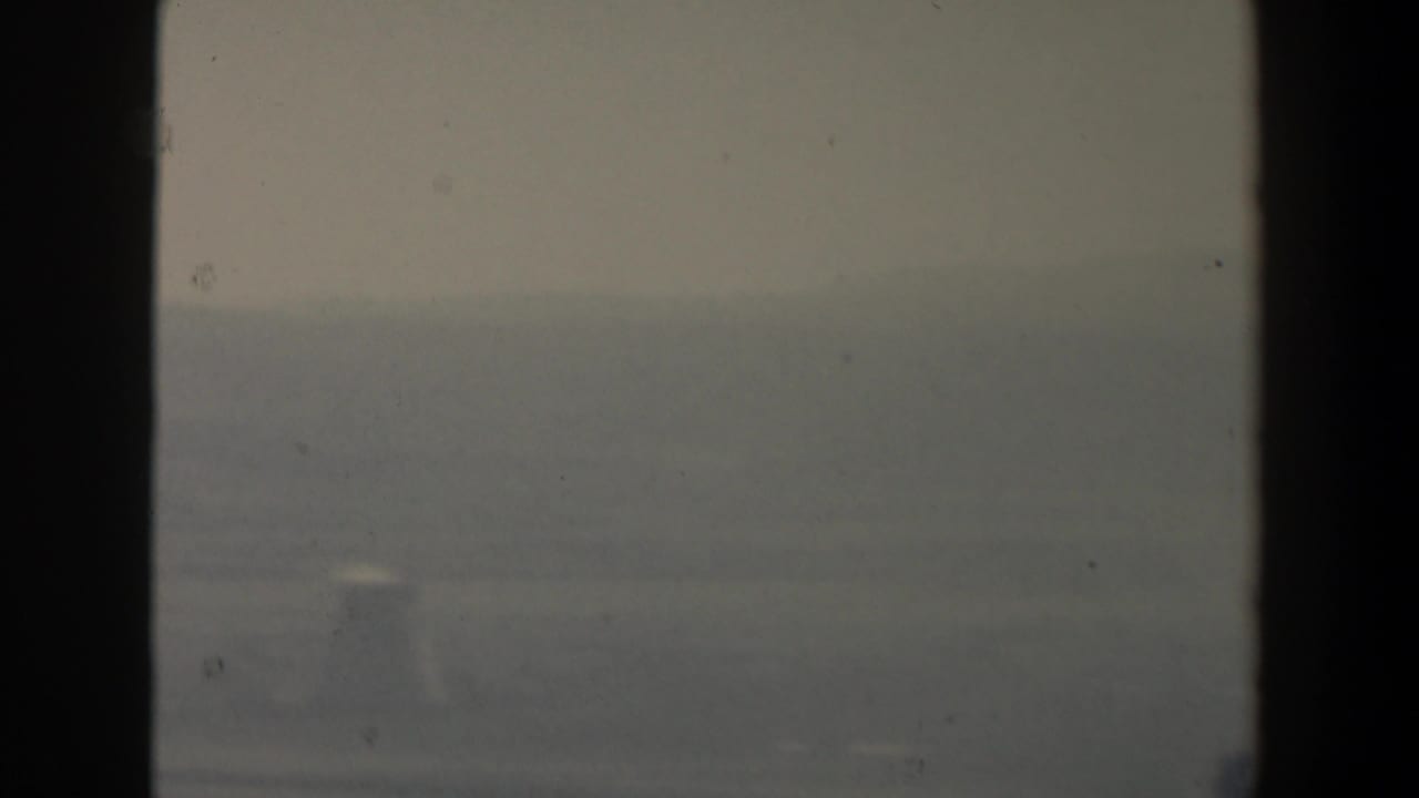 Hazy distant hills seen through dark vertical window bars.
