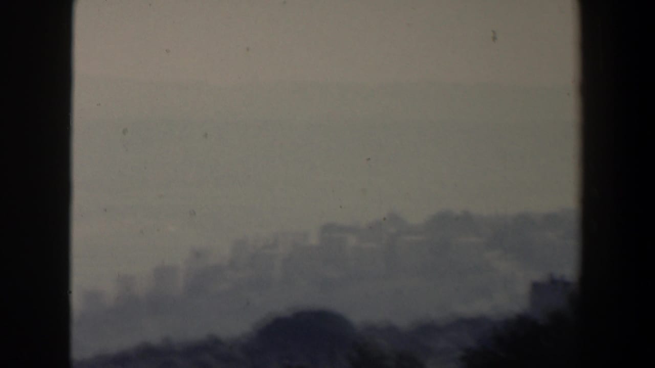 Distant hillside with pale buildings beyond a dark central frame bar.