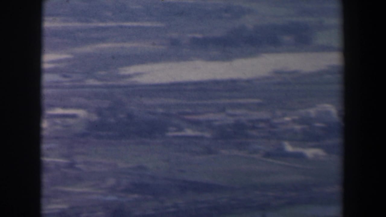 1960 Israel 8mm aerial frame showing open rural terrain with faint roads, fields, and scattered light-toned buildings.