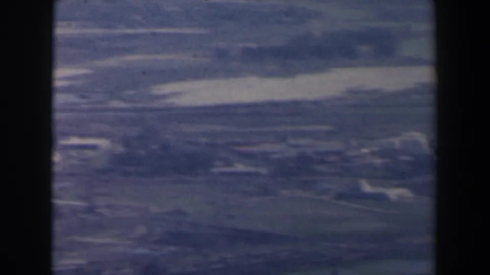 1960 Israel 8mm aerial frame showing open rural terrain with faint roads, fields, and scattered light-toned buildings.