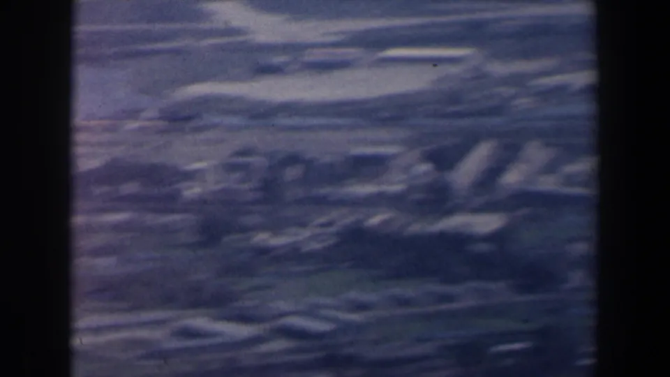 Blue-tinted 1960 Israel aerial frame with fields, winding roads, and indistinct low buildings across rural terrain.