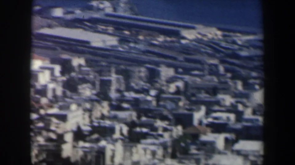 1960 Israel home-movie view over dense rooftops with a possible waterfront or harbor area in the distance.
