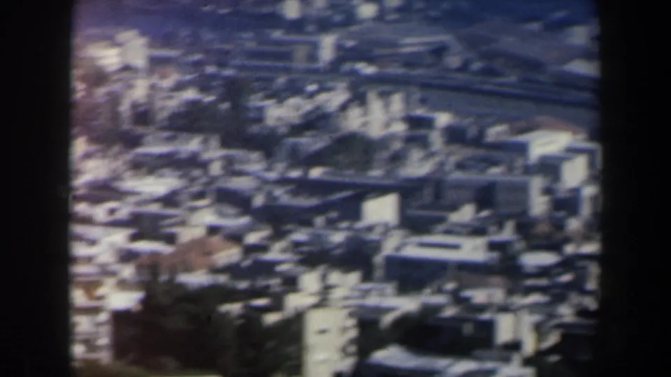 1960 Israel frame showing a soft panoramic view of dense urban buildings, rooftops, and frame-edge shadowing.
