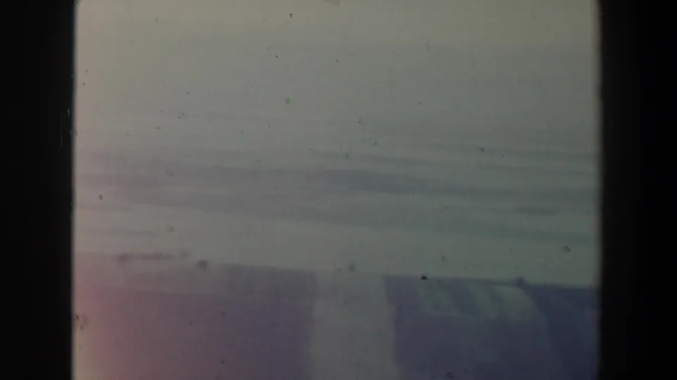 Soft 8mm view of hazy sky and possible coastline or sea in Israel, with faded color and dark vertical frame borders.