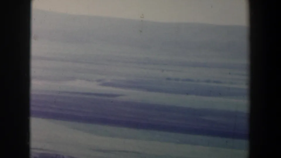 1960 Israel 8mm frame with muted storm clouds, hazy landscape bands, and visible scan artifacts from the film surface.