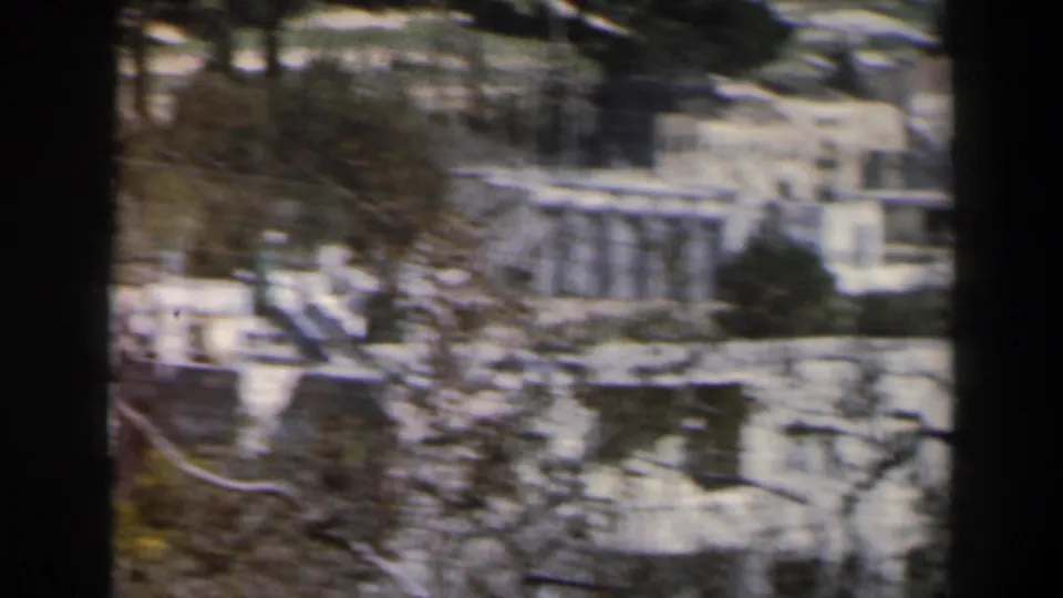 1960 Israel hillside view with white buildings, stone terraces, and vegetation recorded in soft color 8mm.