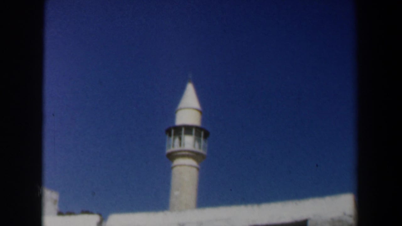 Minaret and white wall framed against a deep blue sky.