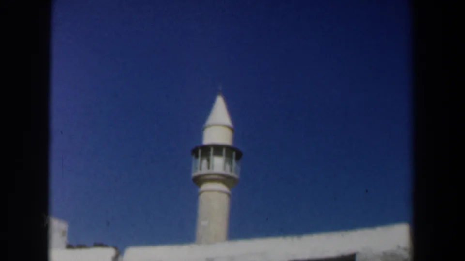 1960 Israel home-movie view of a mosque minaret with white masonry and strong blue sky.