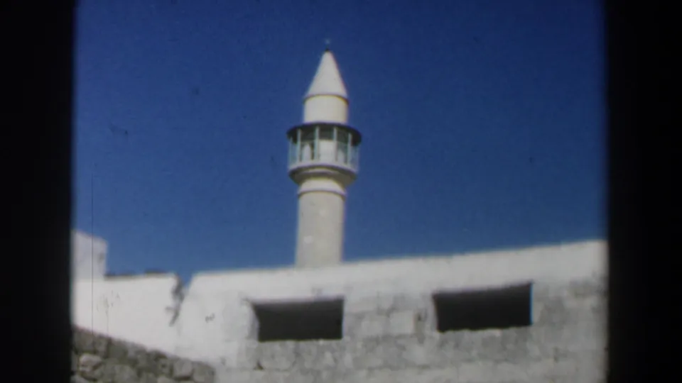 1960 Israel 8mm still with a mosque minaret partly framed by whitewashed and stone walls.