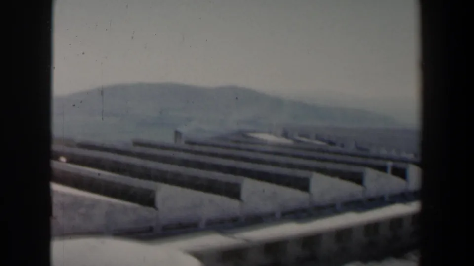 1960 Israel frame with a modern concrete hillside structure, terrace-like edges, railings, and hazy hills beyond.