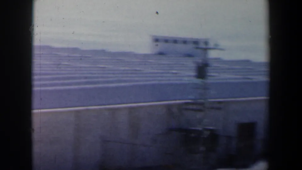 Blurred 1960 Israel 8mm view of repeating ribbed concrete forms behind a low perimeter wall.