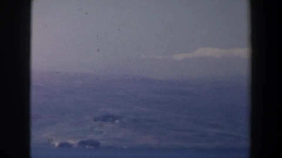 1960 Israel 8mm frame showing distant hills or terrain beneath a low cloud layer, softened by haze and film grain.