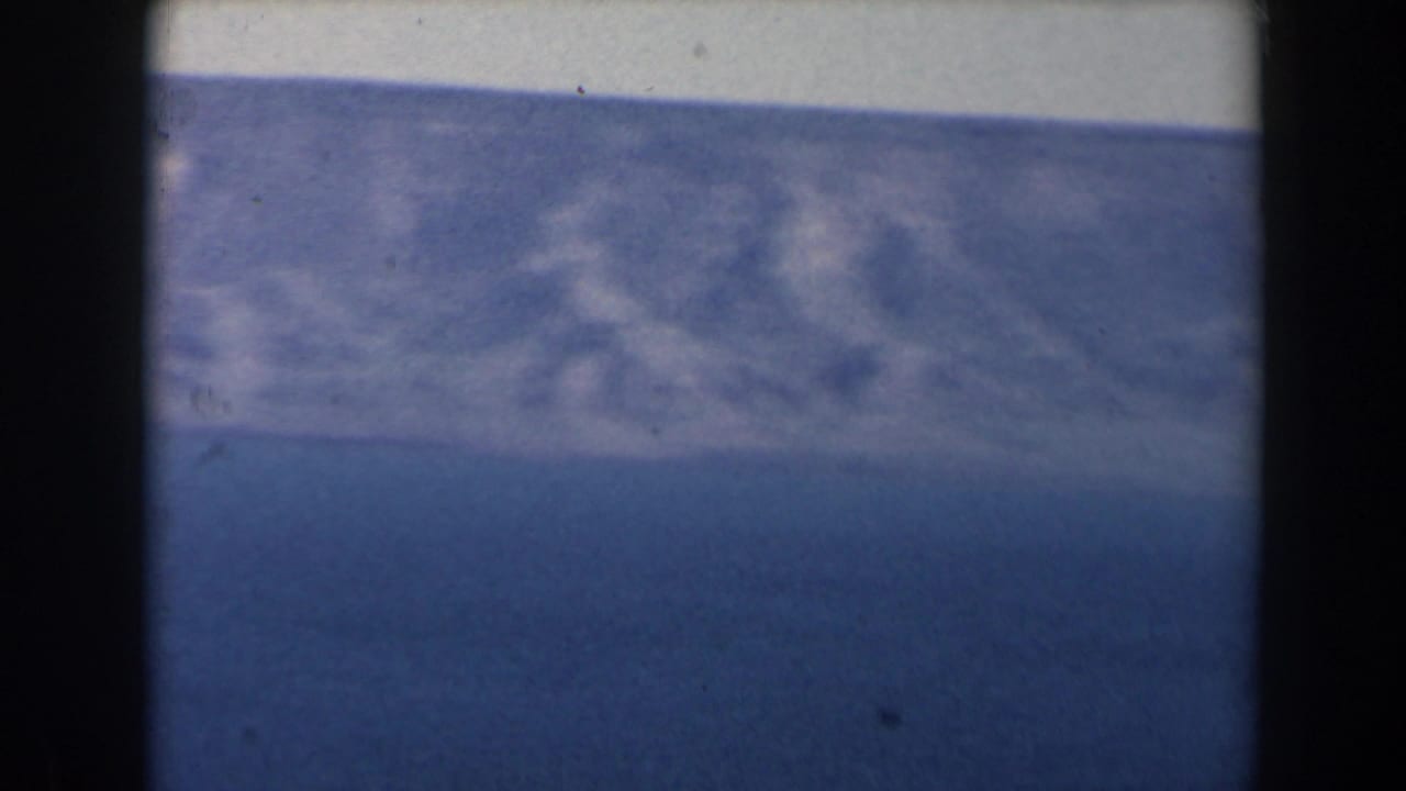Blue sea and hazy horizon seen through dark vertical frame edges.