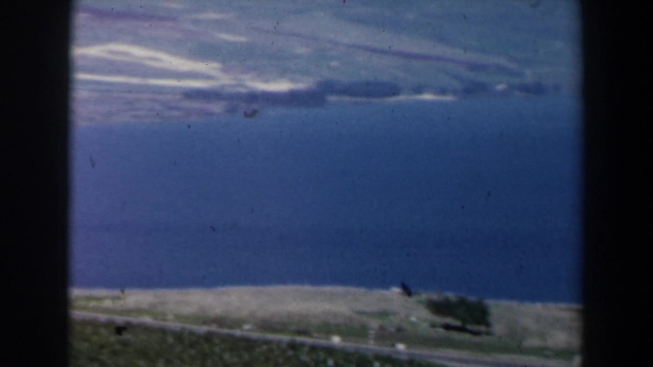 Blue lake and distant hills seen through dark 8mm frame borders.