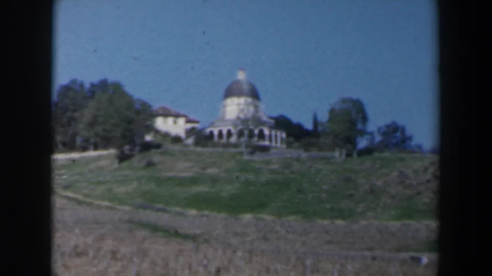 Distant 1960 Israel home-movie view of a domed building on a low hill framed by trees.