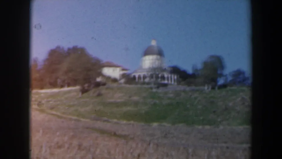 Soft 8mm frame from Israel in 1960 showing a domed building beyond a grassy slope and trees.