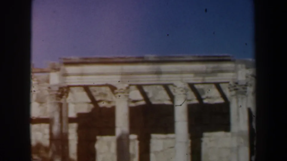 1960 8mm travel frame from Israel showing pale ancient stonework, columns, and shadowed openings under blue sky.