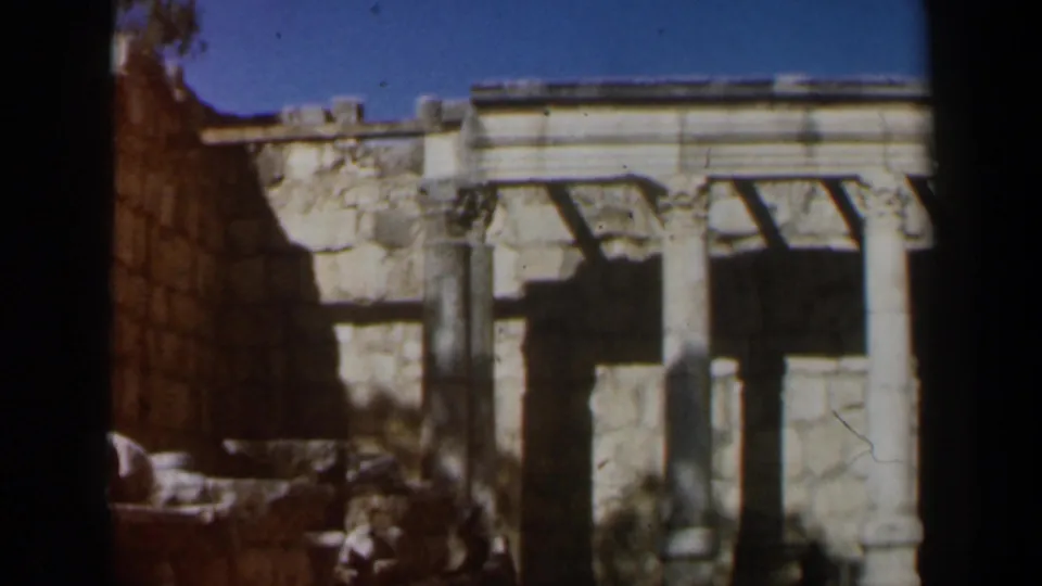 1960 8mm footage in Israel showing a stone passage beside weathered walls and a columned ruin facade.