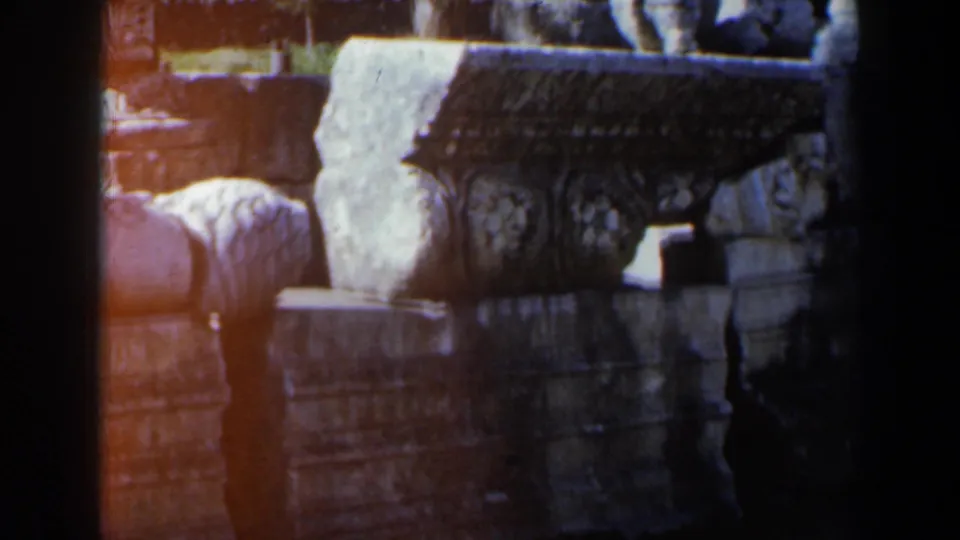 Close 1960 8mm view of carved architectural stonework in Israel, with floral motifs, stacked blocks, and warm exposure flares.