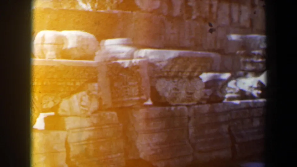 1960 8mm Israel frame of sunlit carved stones and architectural fragments, partly washed by yellow-orange film exposure flare.