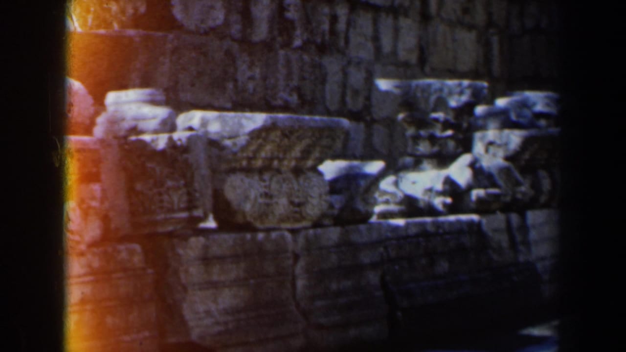 Weathered stone ruins seen close up with dark film borders and warm light leak.