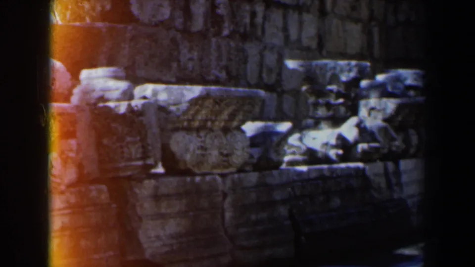 1960 8mm Israel footage showing weathered stone ruins near the water with heavy frame borders and warm light at the edge.
