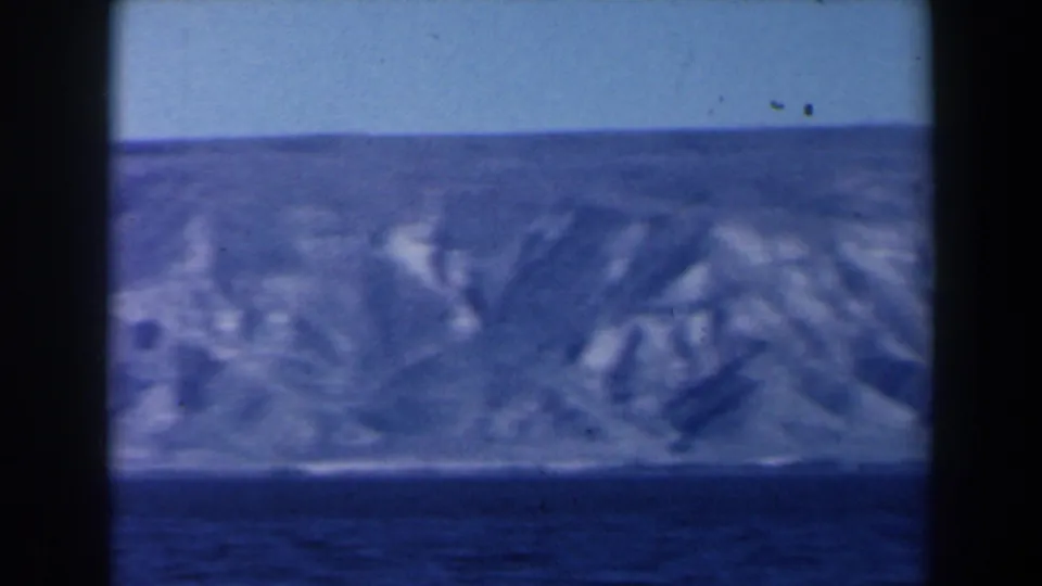 1960 8mm Israel footage looking from the water toward a rugged, pale coastline under a clear blue sky.