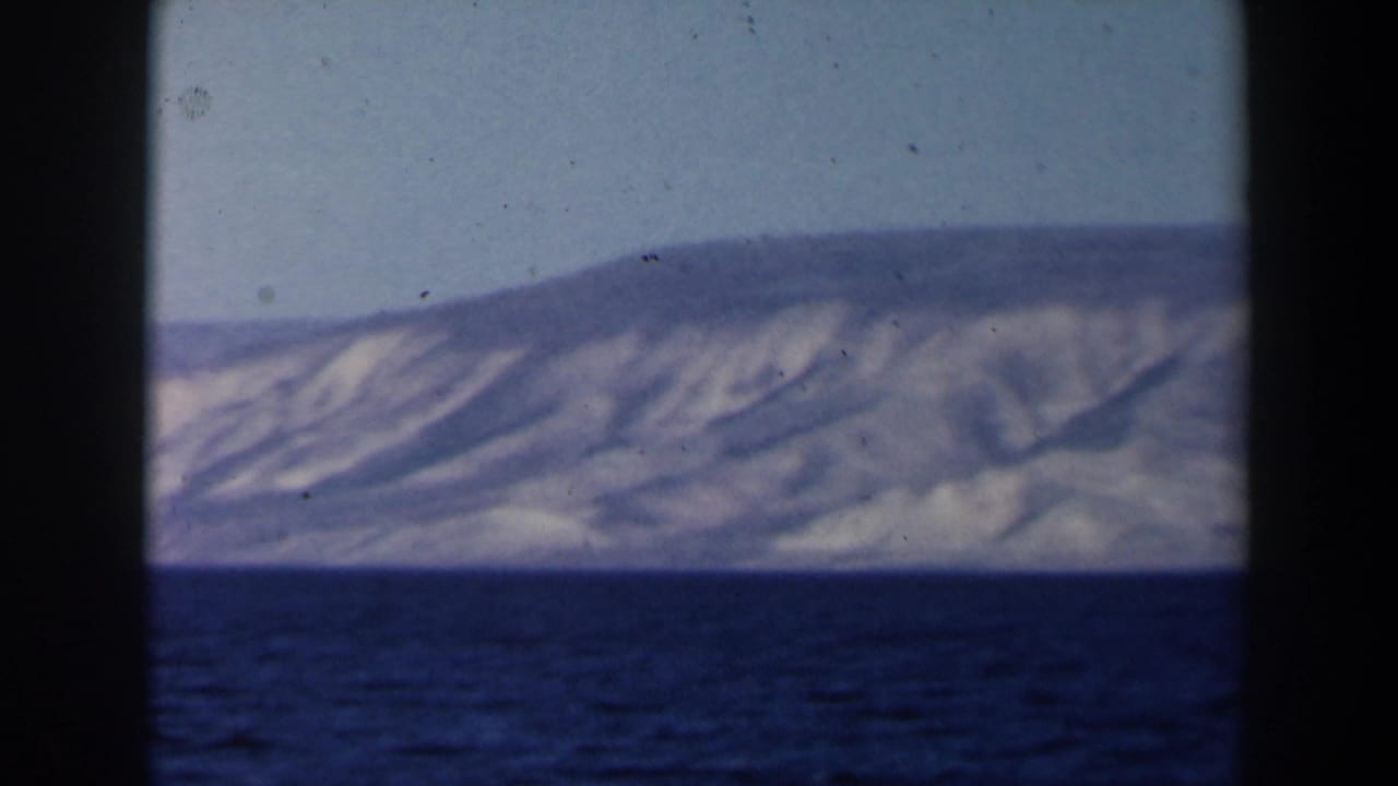 Blue sea and distant sloping hills seen through black 8mm frame borders.