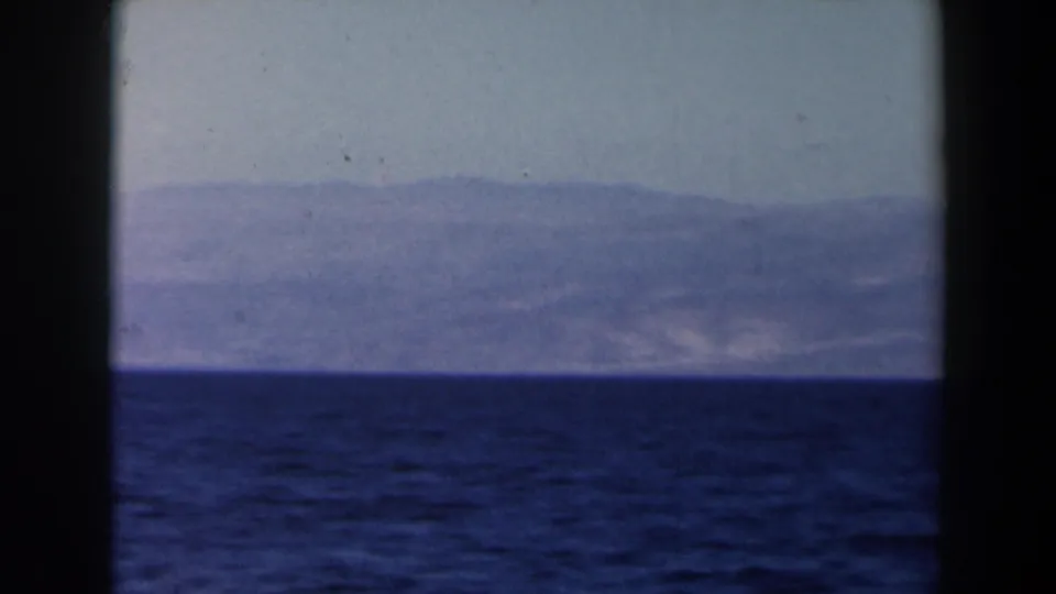 1960 Israel-labeled 8mm frame with dark blue sea, a soft distant coastline, and visible film border edges.