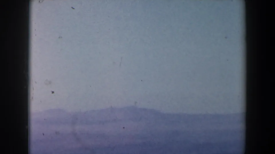 1960 8mm Israel-context footage showing open sea, faint coastline or mountains, pale haze, and dark film-frame edges.