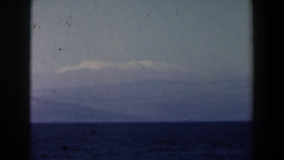 Distant coastline or mountains sit beyond open water in soft 1960 8mm Israel-context travel footage.
