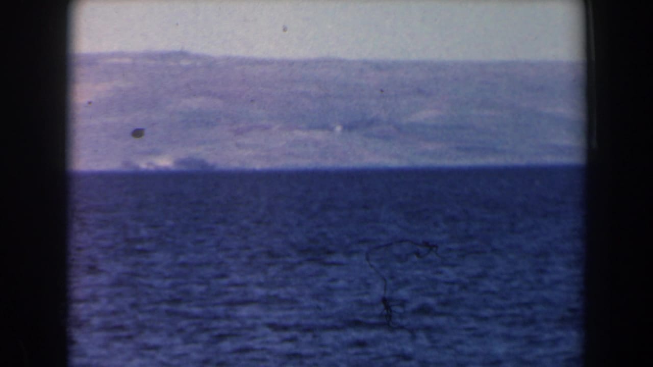 1960 Israel 8mm frame with rippled sea in the foreground and a hazy mountainous coastline beyond the horizon.