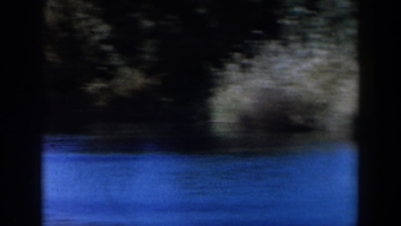 Blurred lake water and dark shoreline seen through 8mm frame borders.