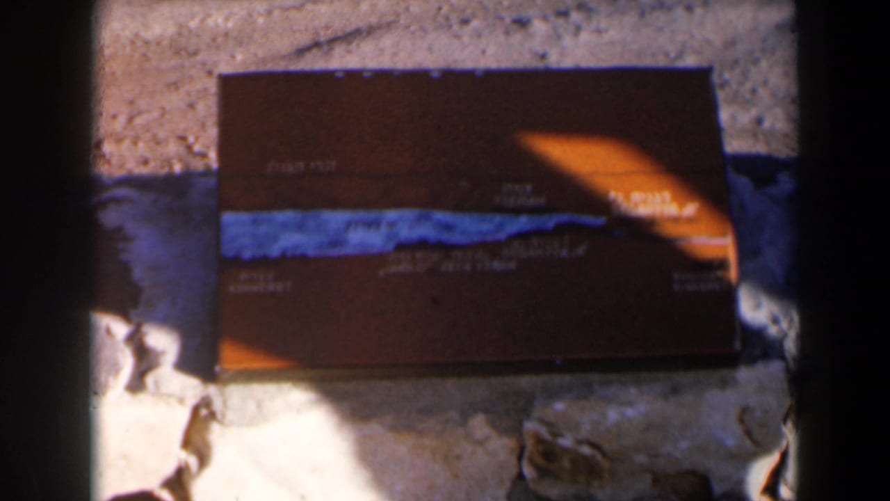 Brown tackle box on rocks with a bright orange patch of sunlight across one corner.