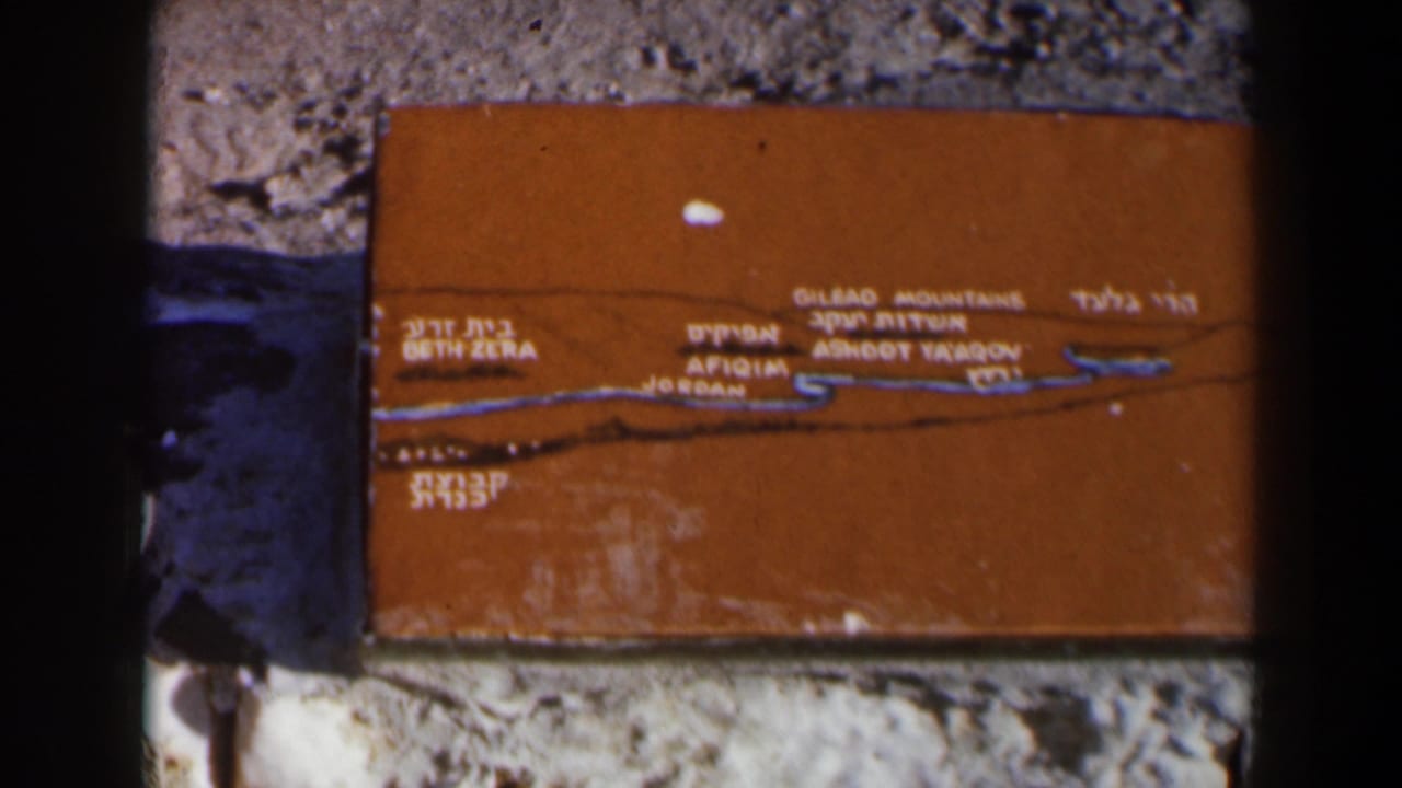 Orange bilingual plaque with a map line mounted on a rough stone wall.