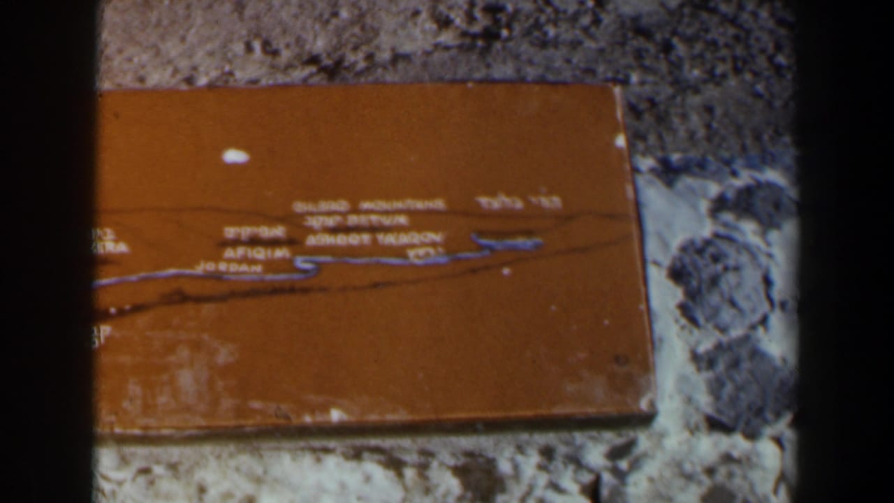 Close view of a weathered orange plaque in a stone wall, filmed on 8mm in Israel around 1960.