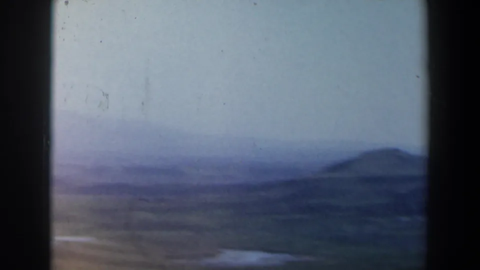 Hazy 1960 Israel landscape view with blue water or valley tones and a low distant hill.