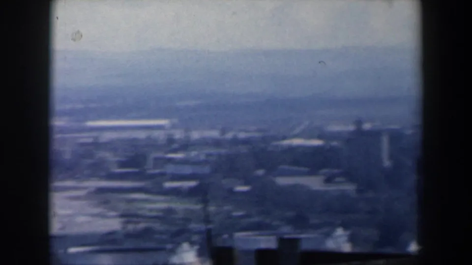 Blue-tinted 1960 Israel home-movie frame showing a broad coastal cityscape and waterfront from above.