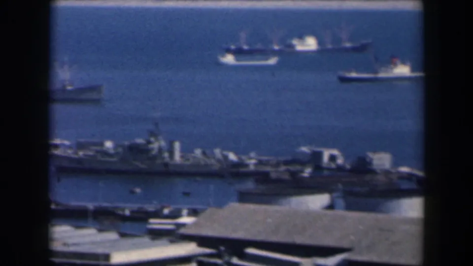 Harbor scene in 1960 Israel with anchored ships, deep blue water, and waterfront roofs below the frame.