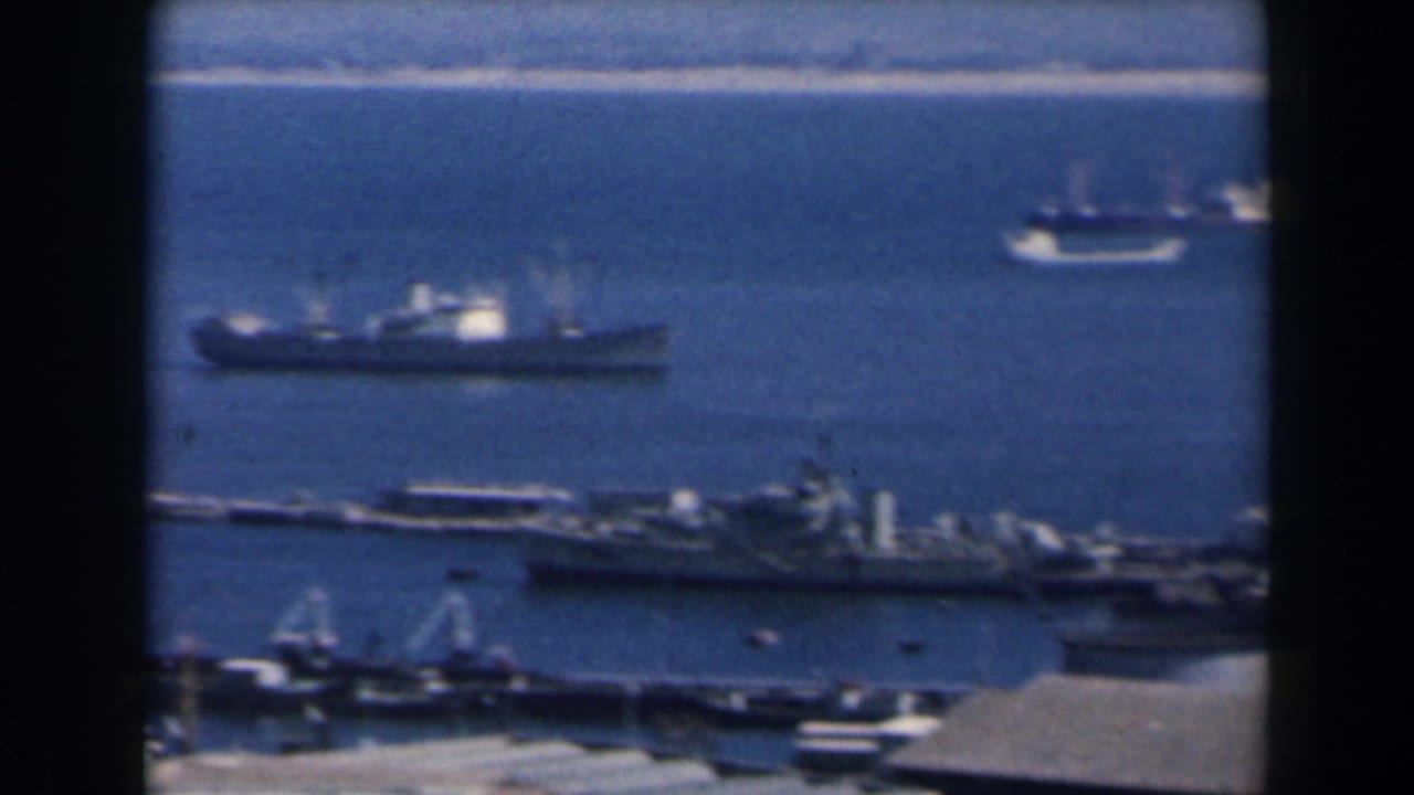 1960 Israel 8mm harbor view with anchored ships, piers, cranes and a distant shoreline seen from above.