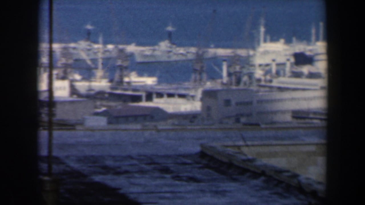 1960 Israel harbor view with docked ships, port structures, blue water, rooftops, and dark window or viewfinder edges.