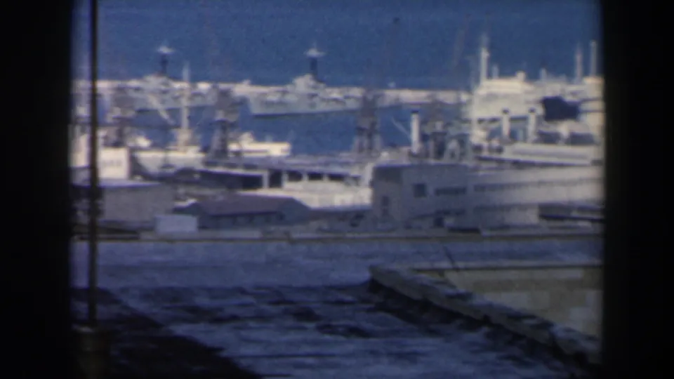 1960 Israel harbor view with docked ships, port structures, blue water, rooftops, and dark window or viewfinder edges.