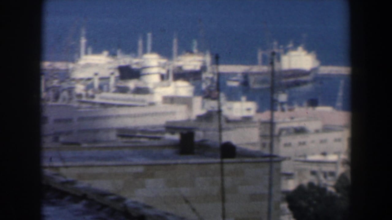 1960 Israel harbor footage showing large docked vessels, piers, cranes, and port buildings from an elevated vantage point.