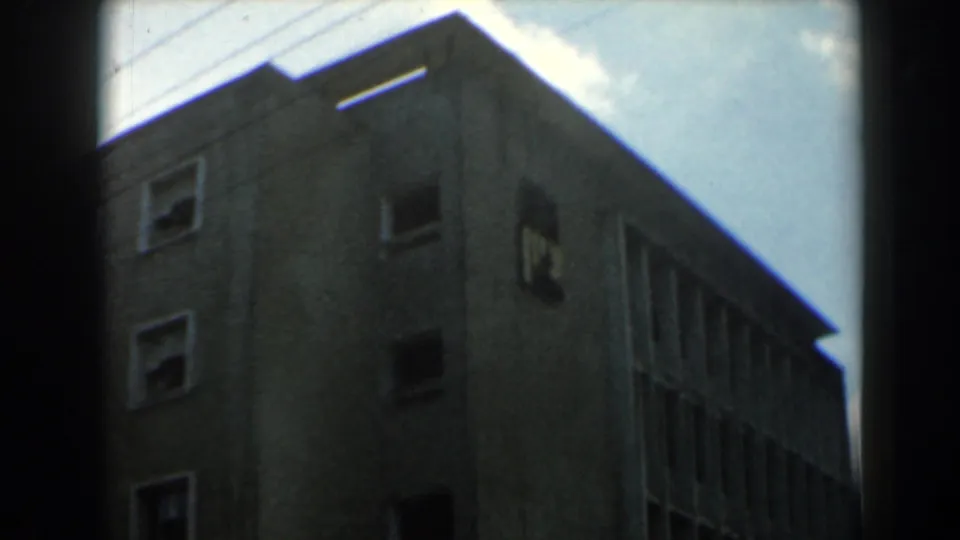 1960 Israel 8mm frame showing the upper stories of a masonry building with square windows and strong shadow.